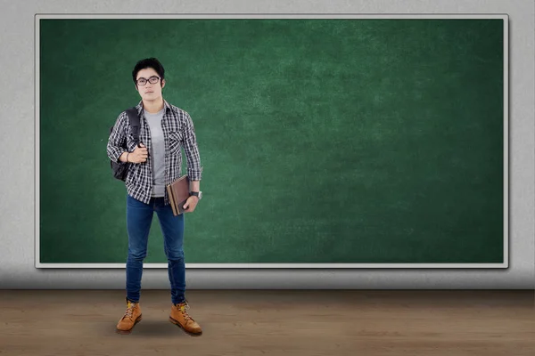 Estudiante masculino sostiene mochila y libro — Foto de Stock