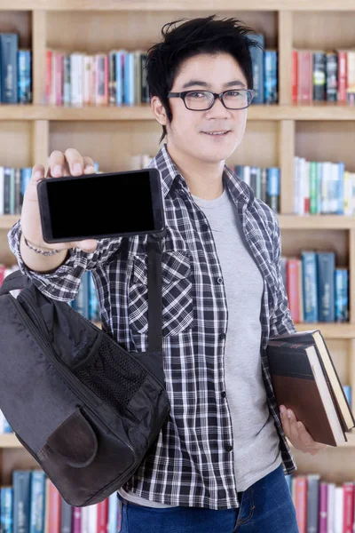 Estudante do sexo masculino mostrando um smartphone na biblioteca — Fotografia de Stock