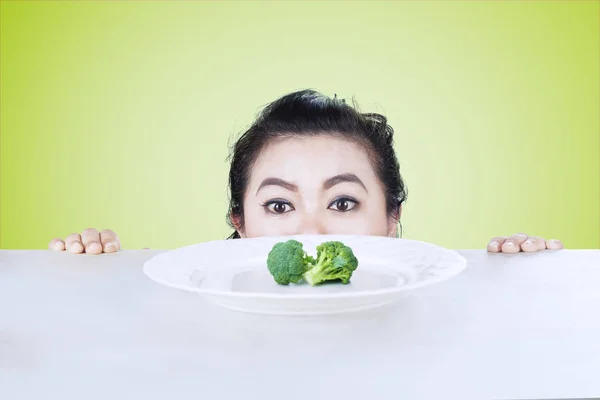 Mulher com excesso de peso a espreitar brócolis — Fotografia de Stock