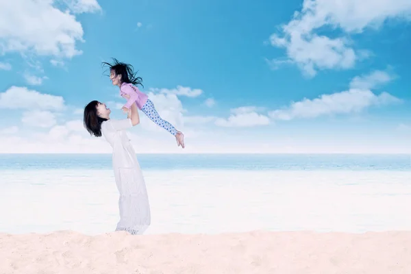 Mujer levantando a su hija en la playa —  Fotos de Stock