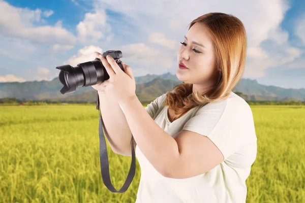 Vrouw op zoek naar digitale camera — Stockfoto