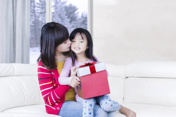 Jeune femme embrasse son enfant avec un cadeau — Photo