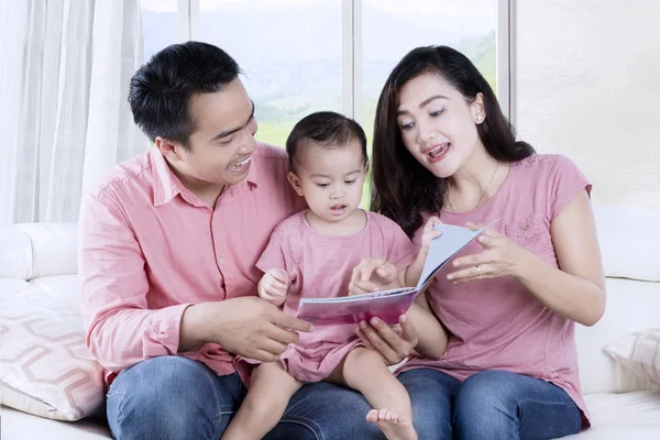 Jeune famille lisant un livre d'histoires à la maison — Photo