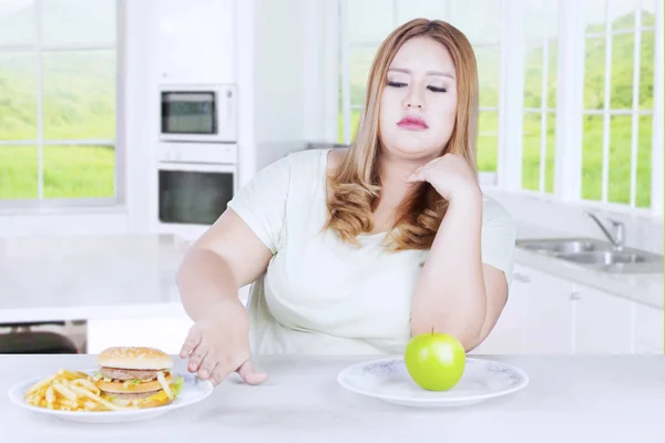 Mulher loira rejeita hambúrguer na cozinha — Fotografia de Stock