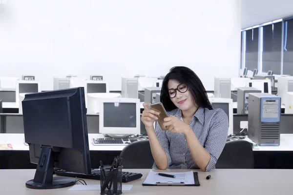 Empresária usando um smartphone no local de trabalho — Fotografia de Stock