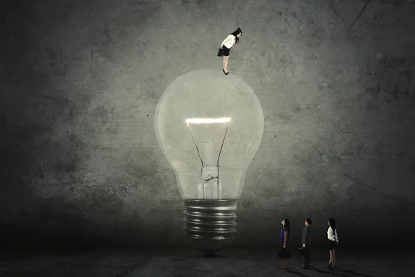 Empresária com lâmpada grande e parceiros — Fotografia de Stock