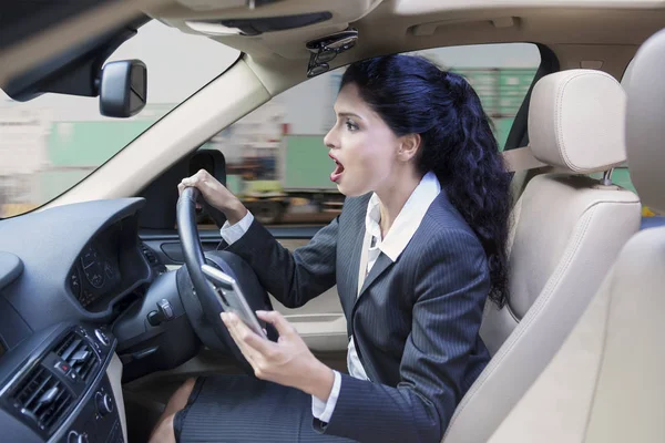 Bizneswoman z cellphone jazdy samochodem — Zdjęcie stockowe