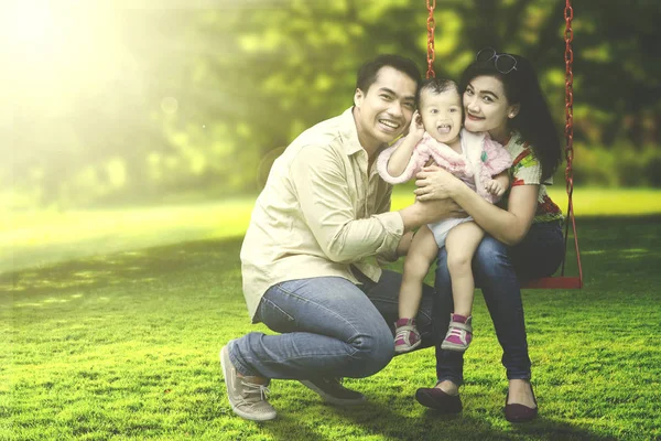 Glad familj leende på swing — Stockfoto