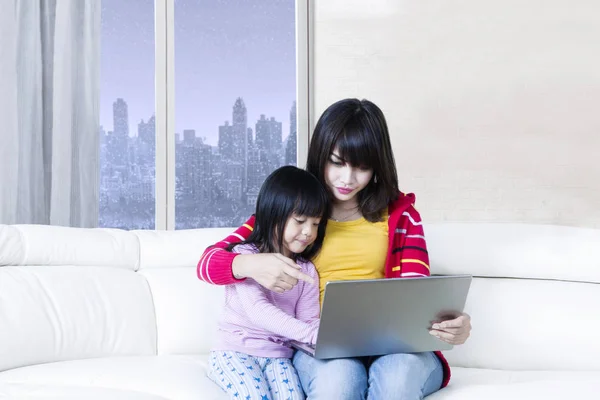 Ребенок и мать используют ноутбук в квартире — стоковое фото