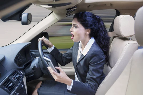 Kvinnlig arbetstagare med mobiltelefon som kör bil — Stockfoto