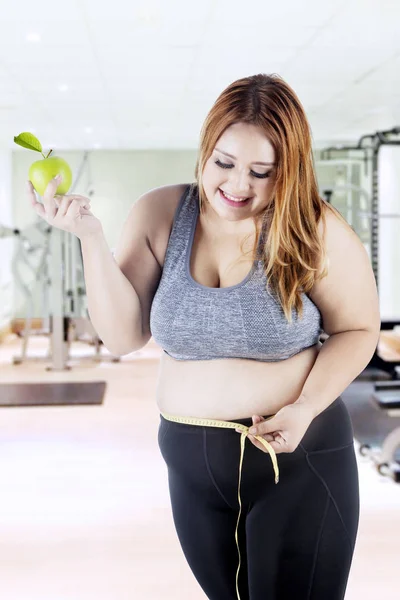 Obese woman measuring her belly at gym — Stock Photo, Image