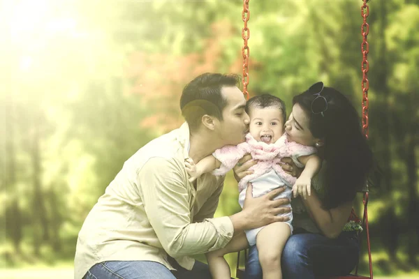 Los padres besan a su hijo en swing —  Fotos de Stock