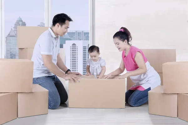 Young parents packing cardboard with their daughter — Stock Photo, Image