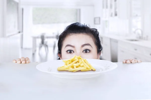 Mujer joven mirando papas fritas — Foto de Stock