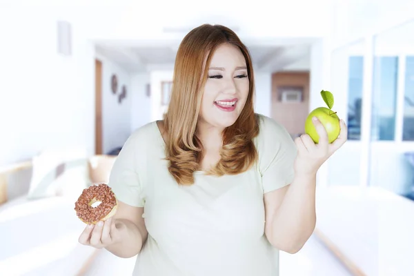 Chica gorda eligiendo manzana o donut — Foto de Stock