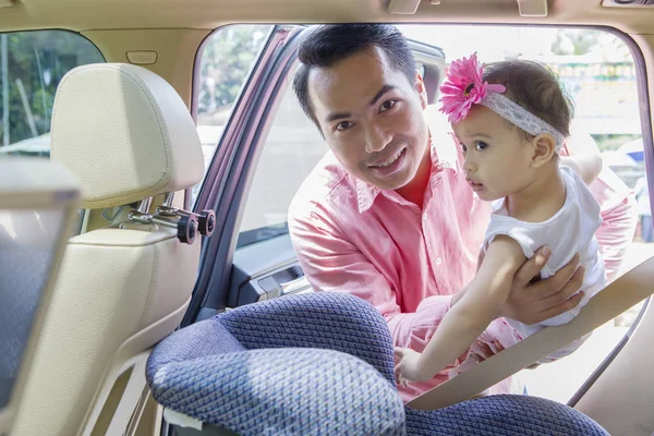 Mann setzt seine Tochter auf Autositz — Stockfoto