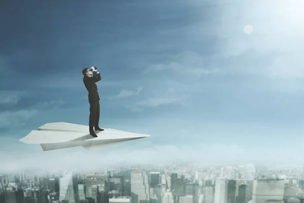 Man met verrekijker vliegen op papier vliegtuig — Stockfoto