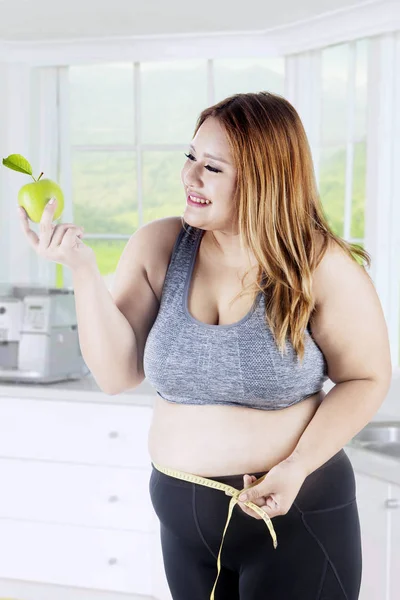 Överviktig kvinna håller apple i köket — Stockfoto