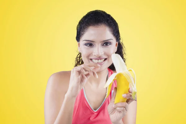 Mulher descascando uma banana no fundo amarelo — Fotografia de Stock