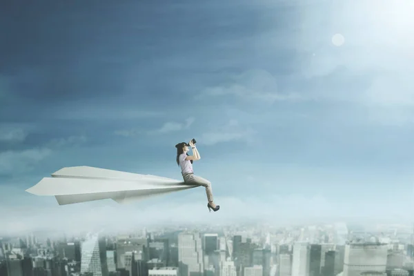 Vrouw met een verrekijker op papieren vliegtuigje — Stockfoto