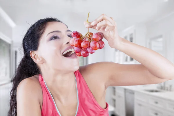 Jeune femme mangeant des raisins à la maison — Photo