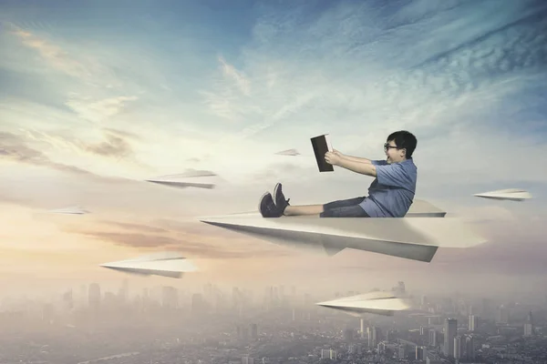 Мальчик летит на бумажном самолете — стоковое фото