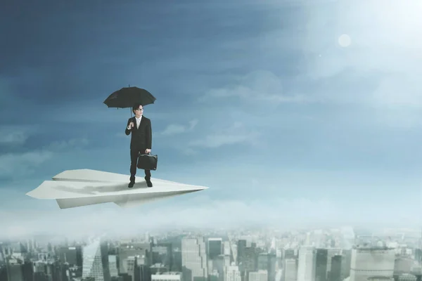 Zakenman met paraplu op papier vliegtuig — Stockfoto