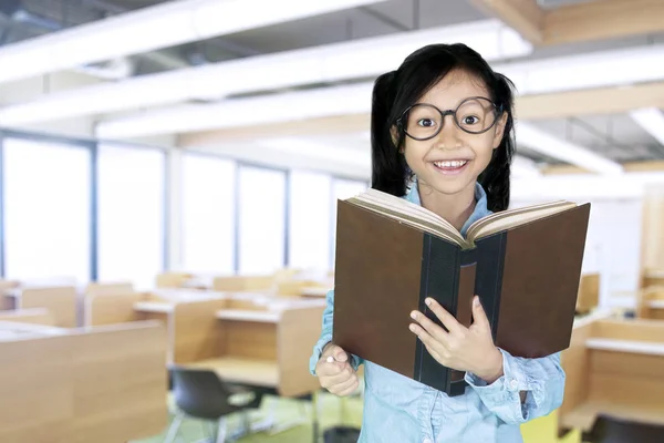 Nettes Mädchen hält Buch im Klassenzimmer — Stockfoto