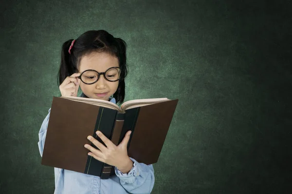 Bonito menina leitura livro no sala de aula — Fotografia de Stock