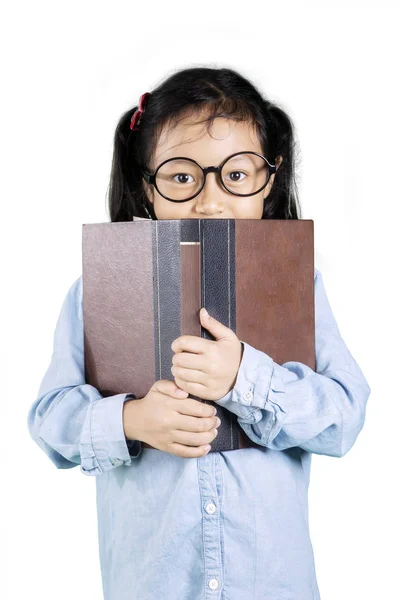 Meisje gluren de camera uit boek — Stockfoto