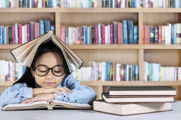 Μικρό κορίτσι διαβάζει βιβλίο στη βιβλιοθήκη — Φωτογραφία Αρχείου