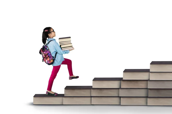 Lilla student håller högen av böcker i studio — Stockfoto