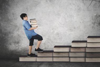 Yığın kitap merdiven üzerinde taşıyan okul çocuğu 