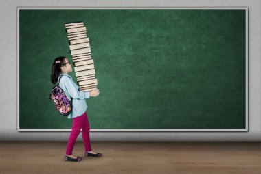Öğrenci sınıfta kitap yığını taşıma 