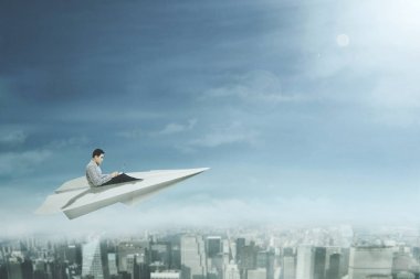 Genç adam dizüstü kağıt uçağa kullanır.