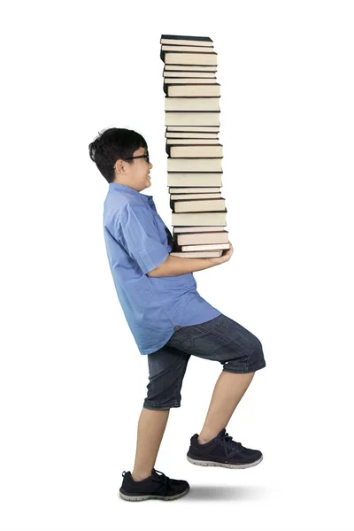 Estudante carregando pilha de livros em estúdio — Fotografia de Stock