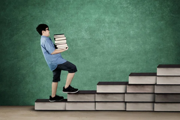 Schoolboy walking on staircase with books — Stock Photo, Image