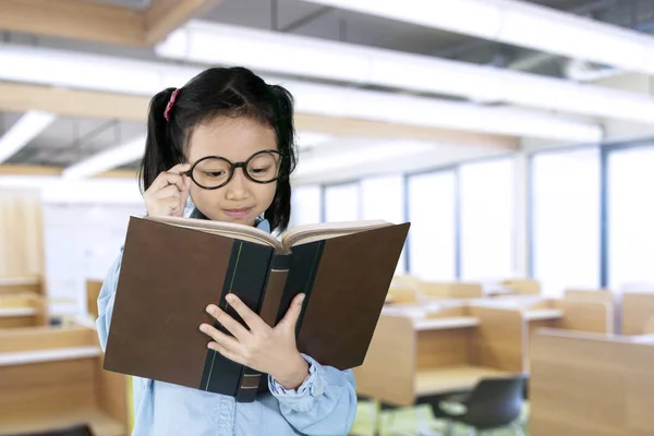 Skolflicka läser läroboken i klassrummet — Stockfoto