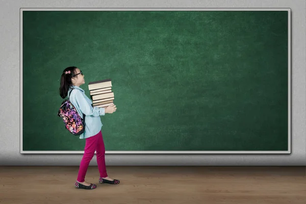 Student som bär högen av böcker i klassrummet — Stockfoto