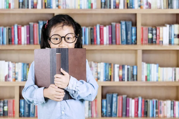 Studentin blickt in Bibliothek hinter Buch — Stockfoto