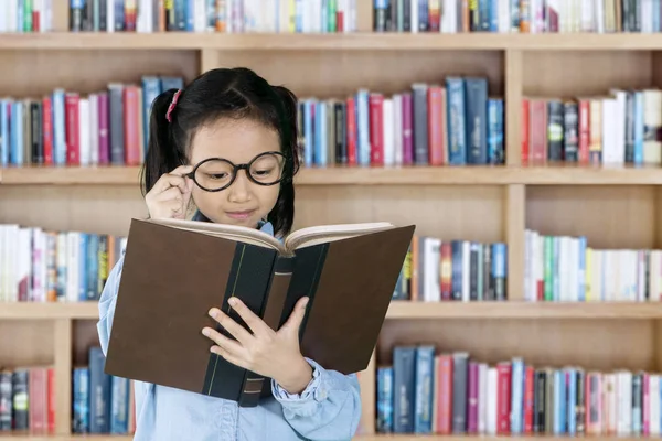 Estudante lendo livro didático na biblioteca — Fotografia de Stock