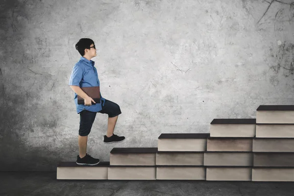 Student walking on books stair with book — Stock Photo, Image