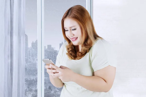 Mujer rubia utiliza teléfono celular en apartamento —  Fotos de Stock