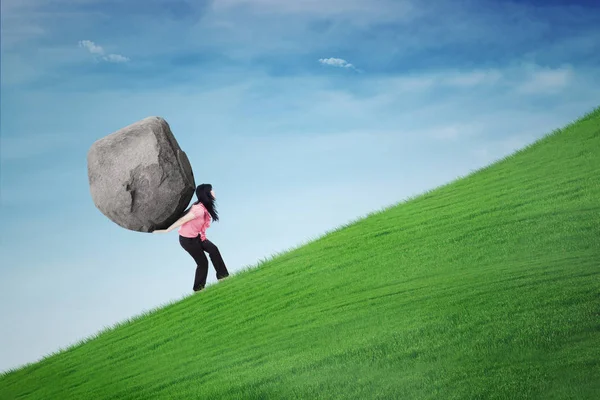 Businesswoman carrying stone on the hill — Stock Photo, Image