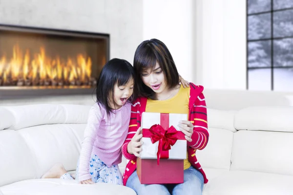Cute girl and mother surprised with gift — Stock Photo, Image
