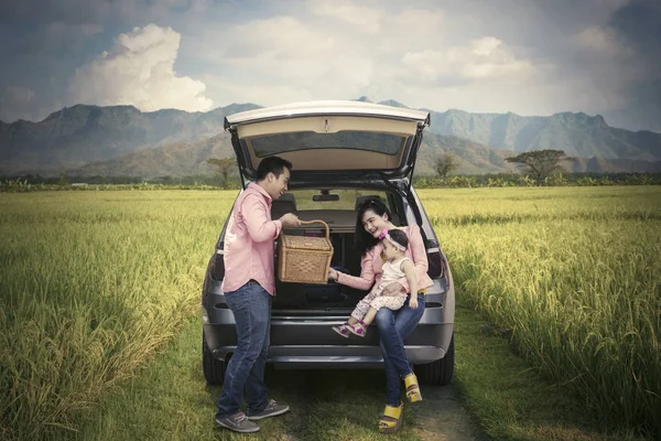 Family holding picnic basket in rice field — Stock Photo, Image