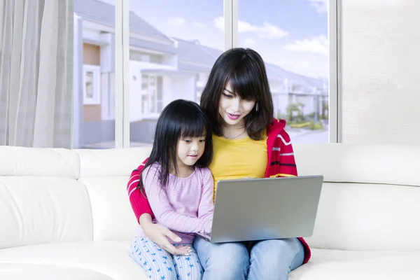 Meisje en haar moeder thuis met behulp van laptop — Stockfoto