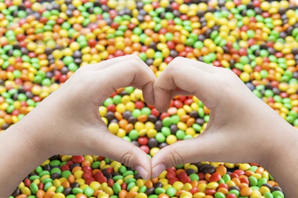 Hands with heart symbol and colorful candies