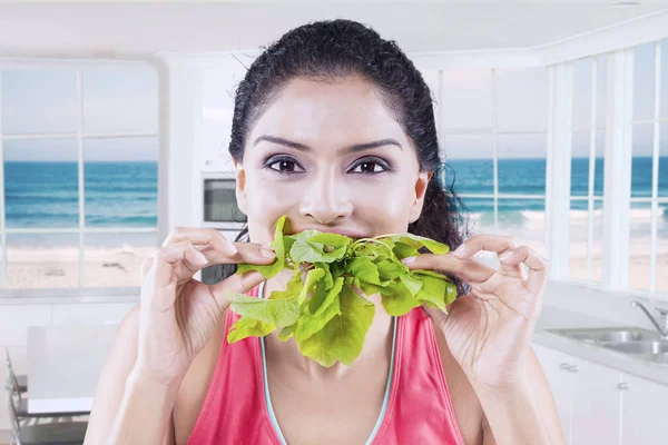 Gelukkige vrouw bijten spinazie met beach achtergrond — Stockfoto