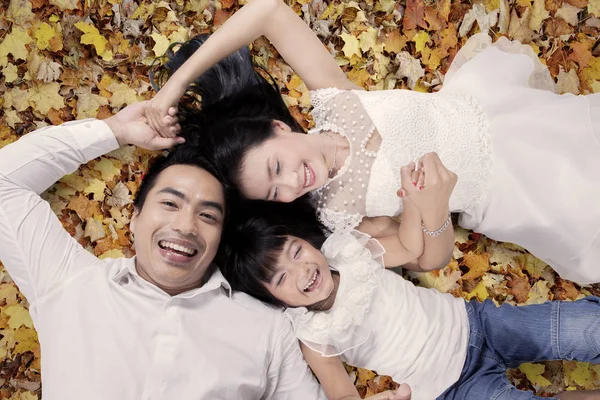Família alegre deitada no parque de outono — Fotografia de Stock